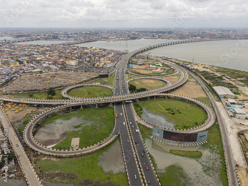Aerial view of a complex cloverleaf interchange with bridges gracefully curving over the landscape, connecting urban areas and the Lagos Lagoon, Lagos, Lagos, Nigeria.