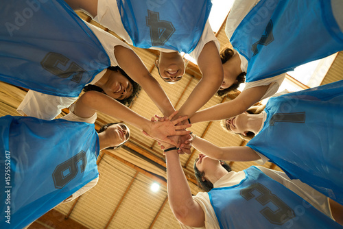 Female basketball team joining hands before game