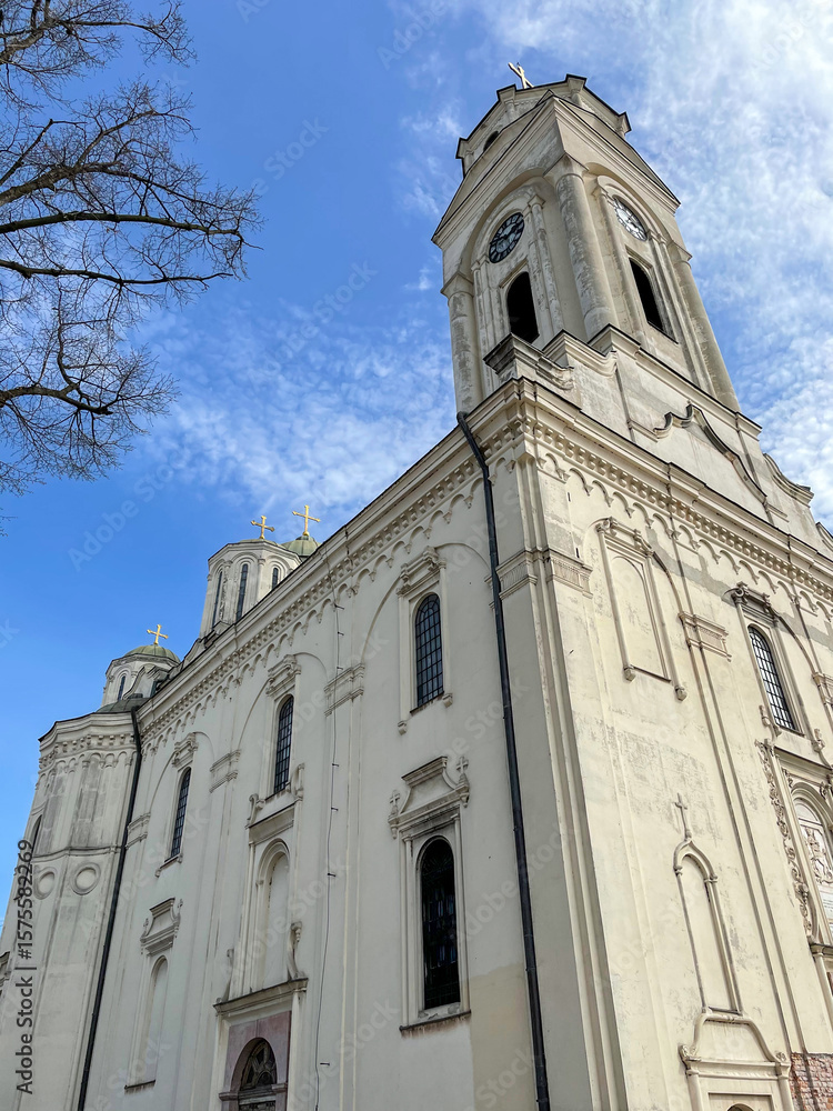 Fototapeta premium Low-angle view of a white church with tall clocktowers and gold crosses.