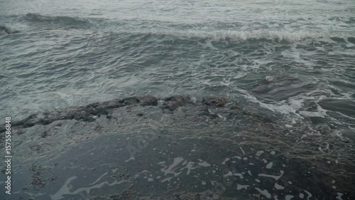 120 fps slow motion and closeup shot of foams created by the ocean waves meet a rocky shoreline.
