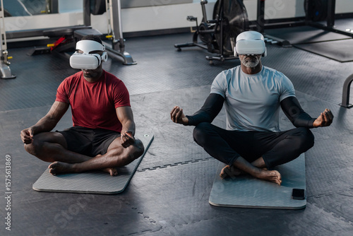 African American men meditating on yoga mats at fitness studio with VR headsets and free weights
