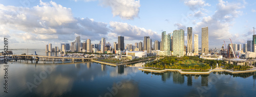 Aerial view of the city skyline reflecting on the water, with a bridge connecting to the mainland, and a vibrant park, Miami, Florida, United States.