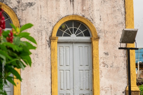 Pale gray door capped by a semicircular fanlight nestles.