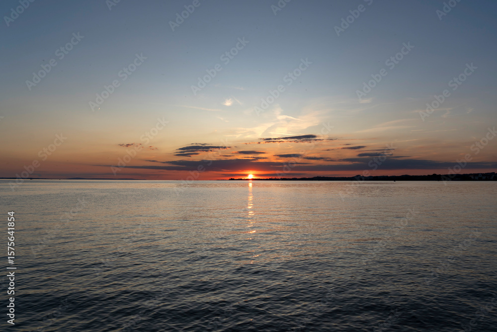 Naklejka premium red and orange sunset over Lake Constance and the island of Lindau in Germany with beautiful clouds seen from the Austrian coastline in Bregenz 