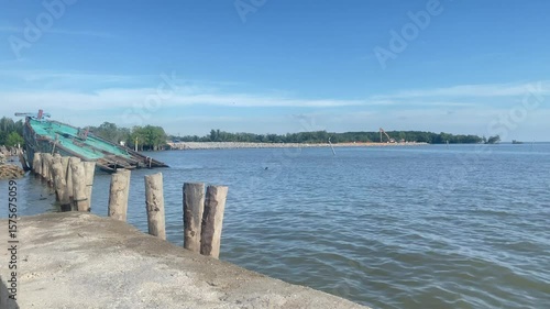 A serene coastal view with a pier and a partially submerged boat.