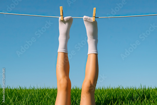 white socks with a legs hanging on a clothesline. Laziness or holiday creative concept