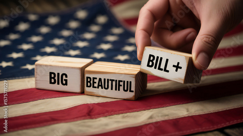 Hand places wooden block with text big beautiful bill on american flag