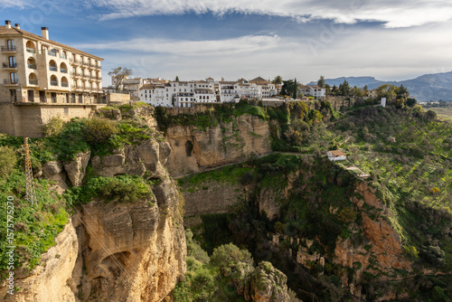 Sunny view of Ronda resting on a cliff, highlighting the depth and dramatic drop of the rocky gorge below. A stunning Andalusian town with breathtaking natural scenery.