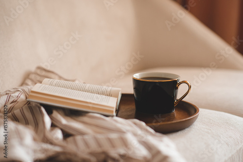 Behang Cup of black tea with open paper book and pajamas shirt cloth on wooden tray in couch in living room close up