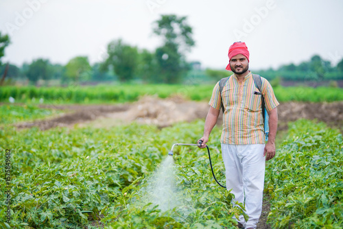 indian farmer spraying pesticide at green field