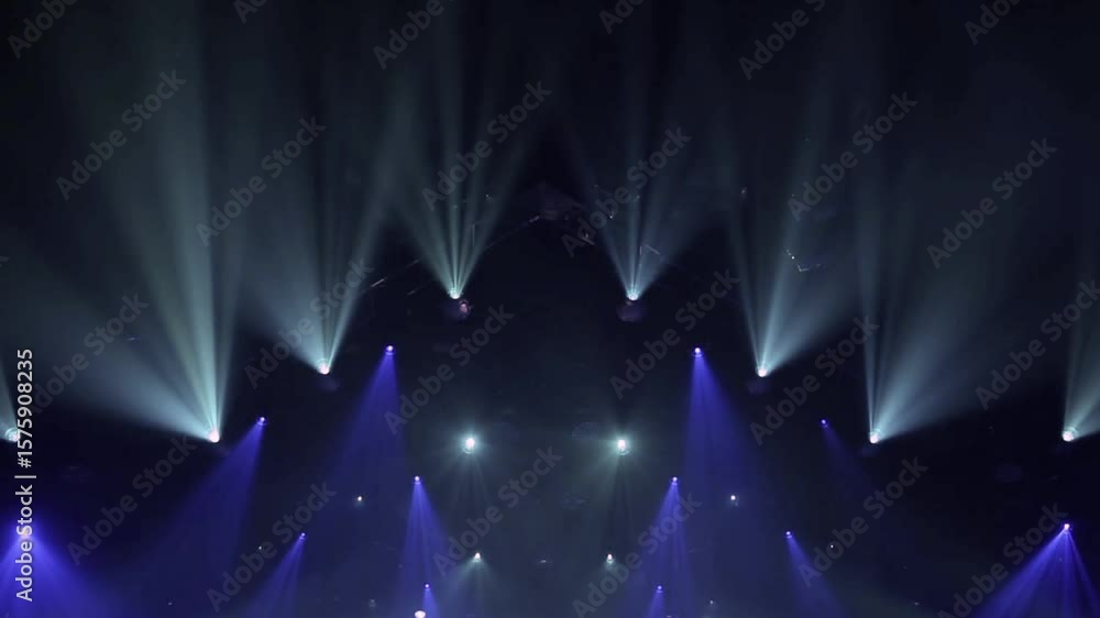 Stage lighting concert beams spotlights dark blue light show dramatic rays powerful illumination performance music event atmosphere