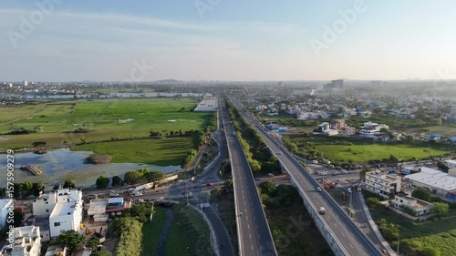 Aerial view of Chennai highway interchange elevated roads, busy traffic, and a mix of residential areas and green spaces. urban infra. flow of traffic and life in a developing Indian metropolis.