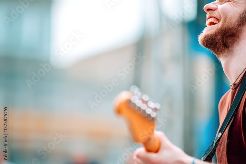 A musician joyfully plays an electric guitar outdoors, his wide smile capturing a moment of pure happiness