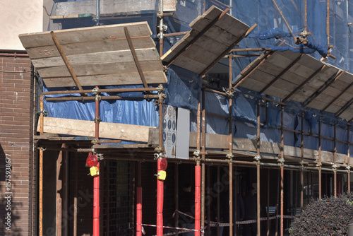 Construction Scaffolding System on Building Site with Safety Equipment and Blue Protective Covering