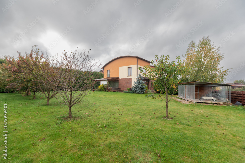 Obraz premium Backyard View with Green Lawn and Residential Homes Under Cloudy Sky