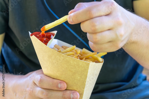 Canvas Print Male dipping french fries into ketchup outdoors