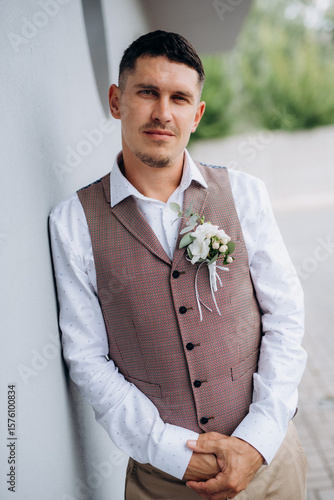 portrait of the groom in a gray suit and an orange vest