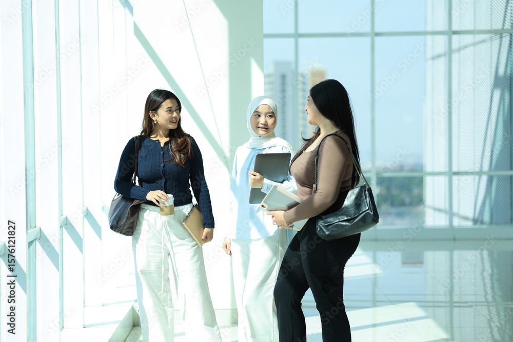 Obraz premium Three Asian Young Colleague Standing at the Big Window, Discussing about Work
