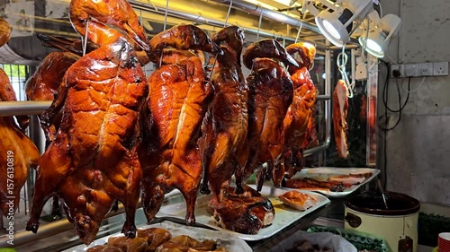 Roast ducks hanging under lights at a Chinese hawker stall, freshly cooked and ready for serving.