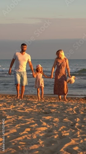 Happy family with child walks on sand beach at sea at sunset. Summer vacation travel holiday. People outdoors by water. Vertical shot