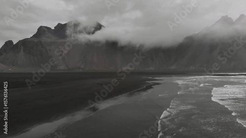 Black sand beach meets the ocean under a cloudy sky