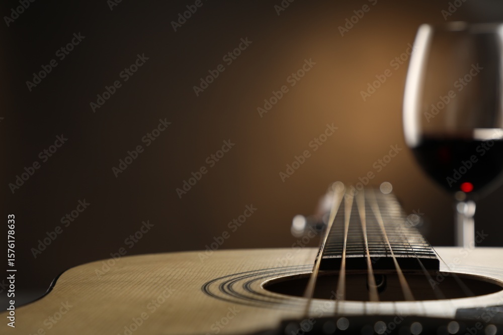 Fototapeta premium Acoustic guitar and glass of red wine on black background, closeup. Space for text