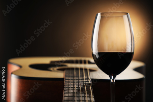 Photography Acoustic guitar and glass of red wine on black background, closeup