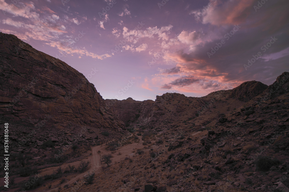 Fototapeta premium Sunset over an arid canyon with pretty clouds