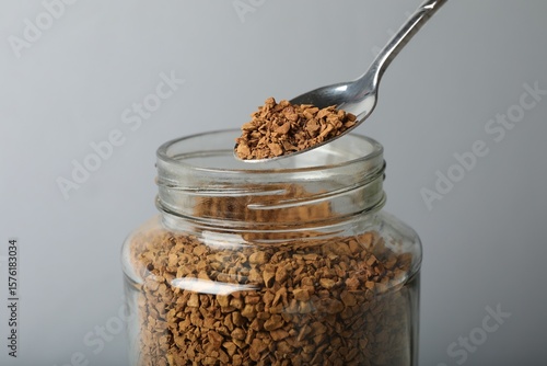 Obraz na płótnie Taking instant coffee with spoon on grey background, closeup