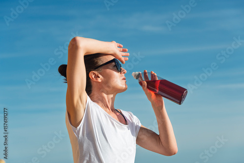 woman drinking an energy from a bottle on a hot day