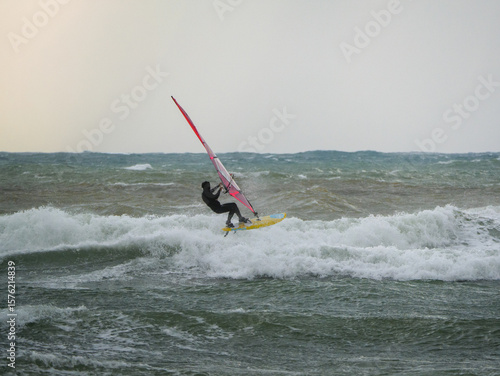 Water Sport Activity - Windsurfer Riding a Wave in Rough Sea on a Windy Day