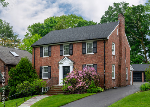 Fototapete Beautiful two-story brick Colonial Revival house with black shutters and floweri