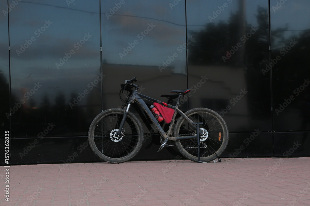 Obraz premium Black spot bike on the city street standing near the glass wall building with pump