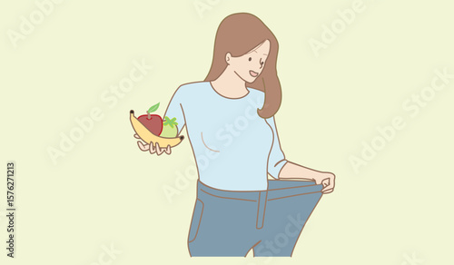 A happy young woman celebrates her successful weight loss and improved health. She is wearing oversized jeans that clearly illustrate her significant body transformation. In her hand, she holds a bana