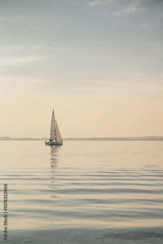 Obraz premium A sailboat on the river near the ocean - a calm, sunny day