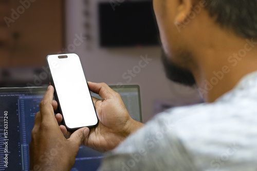 Hand holding portrait view of the smart phone with white background in the home office