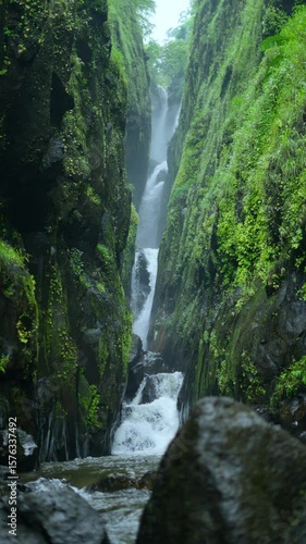 4K Vertical slow motion shot of Saatsada waterfall flowing between the valley of two mountains near Nanemachi in Maharashtra, India. Waterfall flows between the narrow valley in Sahyadri mountains.