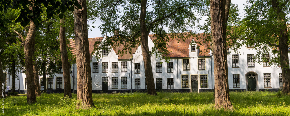 Naklejka premium Beguinage (Begijnhof) with green tree park surrounded by terraced white houses in Brugge in Flanders Belgium