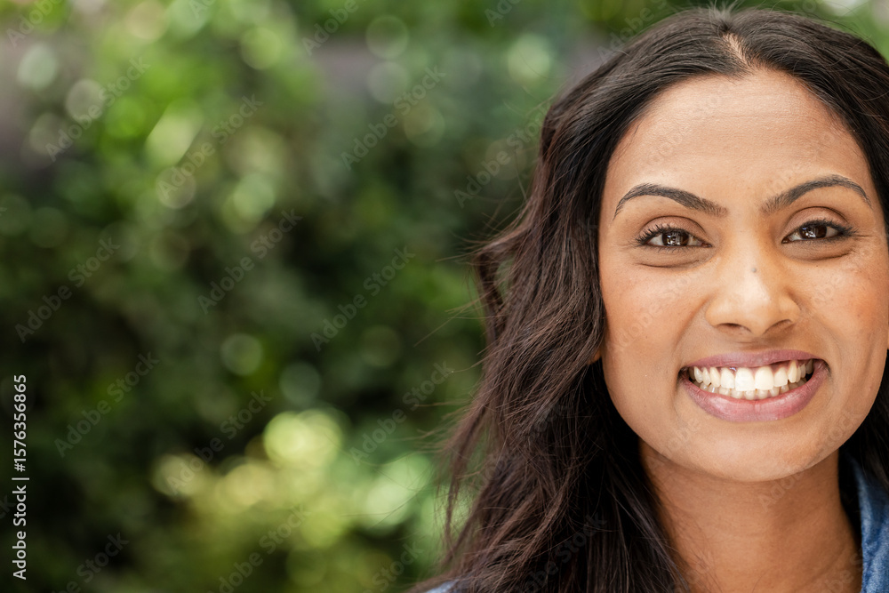 Indian woman in early thirties smiling broadly in garden with lush green foliage, copy space Indian woman in early thirties smiling broadly in garden with lush green foliage, copy space