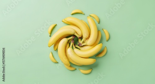 Bananas arranged in spiral shape on light green background, overhead studio shot