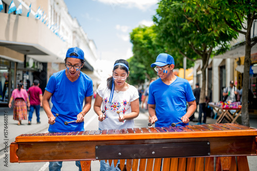 Young Latinos play their country's native instrument. Latino boys play the marimba in the middle of a pedestrian street.