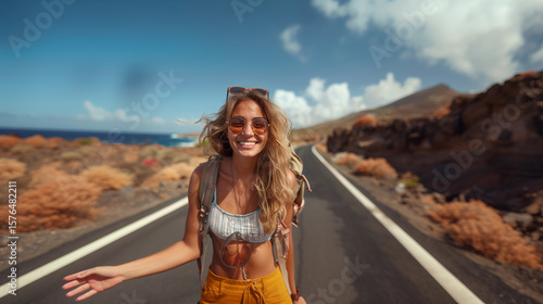 cheerful girl stands on the road and waits for a passing car to travel by hitchhiking