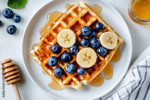 Delicious Breakfast Featuring Waffles Topped With Bananas, Blueberries, and H...