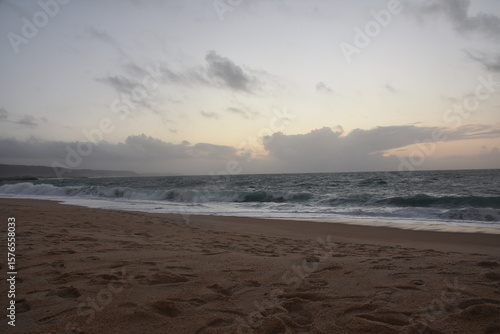 Wallpaper Mural Waves crash onto the shore at Praia do Norte in Nazaré, Portugal, under a cloudy sunset sky—famous for its giant waves and dramatic ocean views. Torontodigital.ca