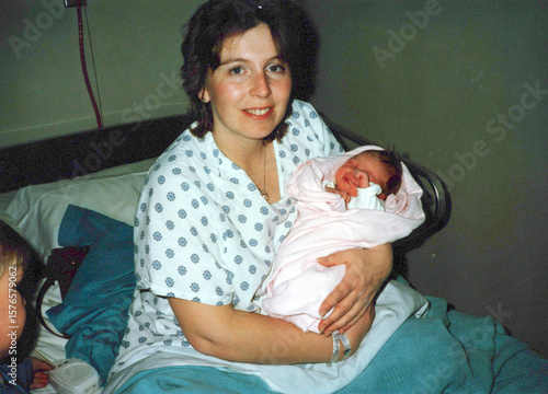Circa 1985 - New mom holds her newborn daughter at the hospital in the 1980s. Image is a vintage scan and may have imperfections