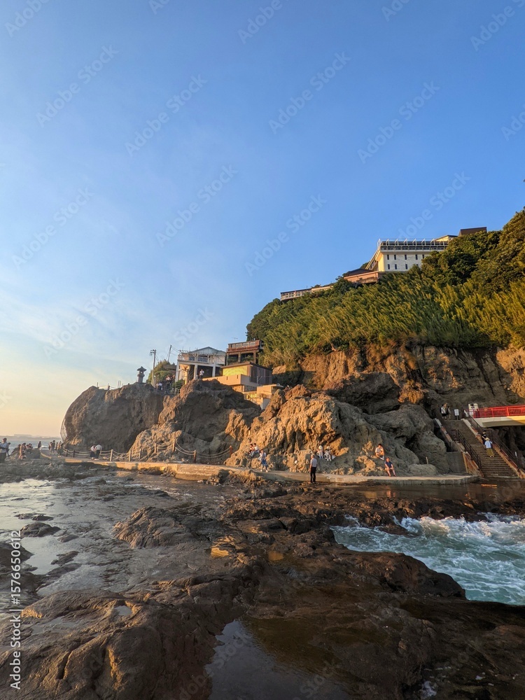 Naklejka premium Seaside Cliffs with Traditional Buildings at Sunset in Japan