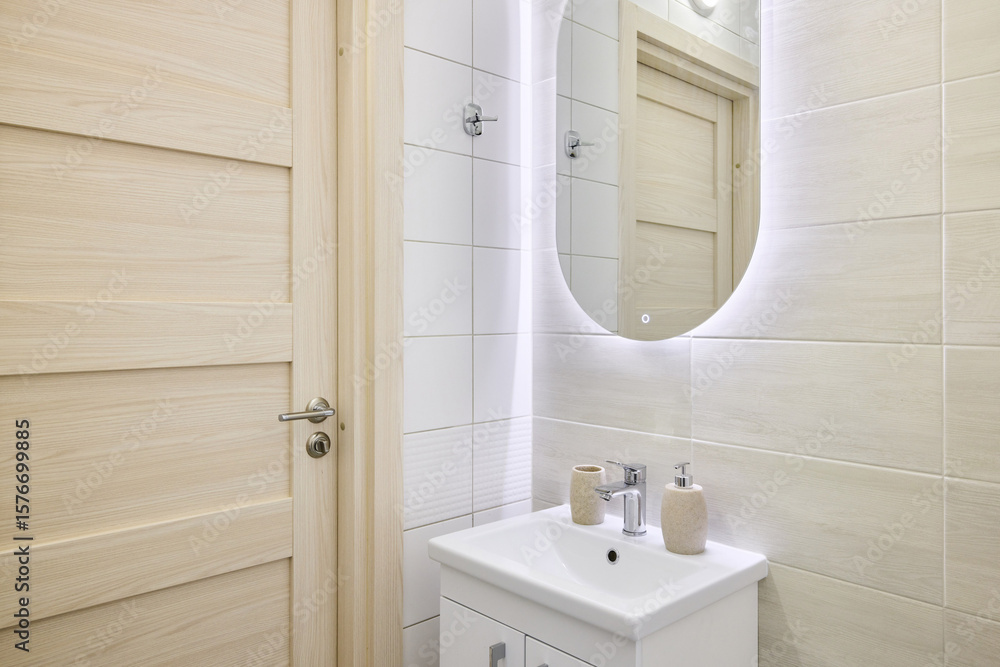 Obraz premium This is a Modern Bathroom featuring a Stylish Sink and an Illuminated Mirror for ambiance