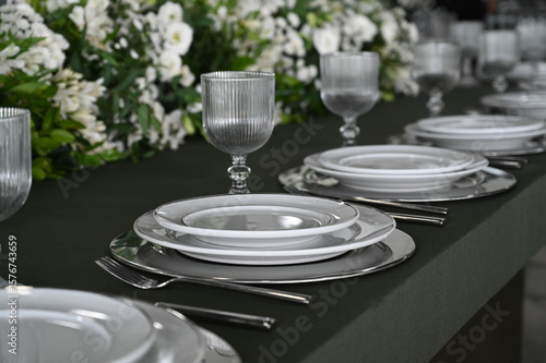 table set in ballroom, elegant wedding reception table with candlesticks, luxury dinner arrangement with floral centerpiece, formal dining table with clear chairs and silver candelabras
