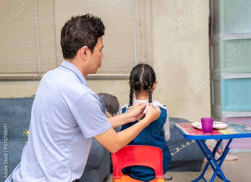 Quadro em tela Father does his little daughter's hair in the living room in the morning before she goes to school