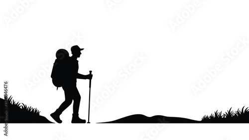 Silhouette of a hiker with a backpack and trekking pole walking on a grassy hill